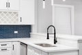 A white kitchen detail with a blue tile backsplash and black faucet. Royalty Free Stock Photo