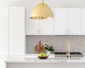 A white kitchen detail with gold light and faucet.