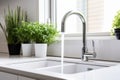 White kitchen faucet with a white sink and green plants in a stylish modern kitchen