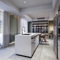 White kitchen island in a modern kitchen with a large glass sideboard with crockery with kitchen furniture in brown