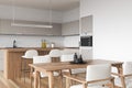 White kitchen set interior with table and seats, shelves and kitchenware Royalty Free Stock Photo