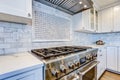 White Kitchen with stainless steel hood over gas cooktop.