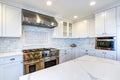 White Kitchen with stainless steel hood over gas cooktop.