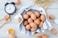 White kitchen table with fresh raw eggs, yellow yolk eggs, white heart shape sign and classic vintage clock. Royalty Free Stock Photo