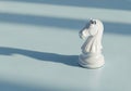 White knight chess piece casting shadow on light blue surface Royalty Free Stock Photo