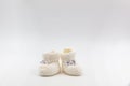 White knitted baby booties with bows on a gray  background Royalty Free Stock Photo