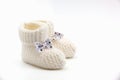 White knitted baby booties with bows on a gray isolated background Royalty Free Stock Photo