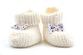 White knitted baby booties with bows on a gray isolated background Royalty Free Stock Photo