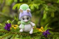 A white knitted bunny is sitting by a green Christmas tree. Royalty Free Stock Photo