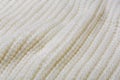 White knitted fabric, laid out diagonally with large folds, selective focus