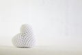 A white knitted heart lies on a white background