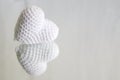 A white knitted heart is reflected in the mirror on a white background