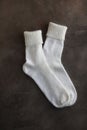 White knitted natural wool socks on a beige and gray table.