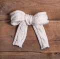 White knitted woolen bow on square wooden background