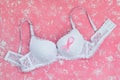 White lace bra with breast cancer awareness ribbon on a pink background with white spots. Pink ribbon of cancer awareness and Royalty Free Stock Photo