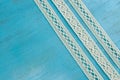 White lace ribbons on blue wooden background.