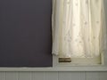 White Lace satin curtain hanging on window with sunlight semitransparent, vintage light purple wall and white siding decoration in Royalty Free Stock Photo