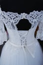 White lace wedding dress on a mannequin. Upper back. Clasp with pearls. Details of the bride`s attire at a wedding ceremony. Royalty Free Stock Photo