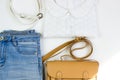 White lace women`s blouse, blue jeans, a brown handbag and a white belt on a white background. Women`s casual outfits. Flat lay, Royalty Free Stock Photo