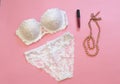 White lacery lingerie near lipstick and necklace on pink background. Woman underwear for special occasions. Composition for beauty Royalty Free Stock Photo