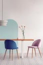 White lamp above long wooden table with vases and stylish chairs