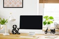 White lamp next to computer desktop on wooden desk in home office interior with plant. Real photo Royalty Free Stock Photo