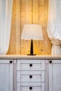 White lamp on the warderobe with raw wooden wall