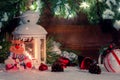 White lantern with a burning candle stands in the snow surrounded by Christmas decorations on the background of a wooden Royalty Free Stock Photo