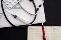 white laptop on which a stethoscope, pills, syringe, thermometer and a side notebook with a pen Royalty Free Stock Photo