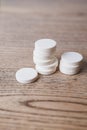 White large pills close up stand in a pile on a wooden background. Vitamins, pharmaceuticals for the treatment of diseases