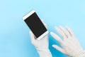 White latex medical gloves on a human`s hand,touching blank screen mobile phone isolated on blue background Royalty Free Stock Photo