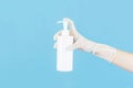 White latex medical gloves on a woman hand,holding a spay killed the disease or alcohol bottle outstretched isolated on blue Royalty Free Stock Photo