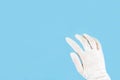 White latex medical gloves on a woman hand outstretched isolated on blue background