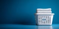 White laundry basket filled with folded white towels against a solid blue background with clean minimalist composition Royalty Free Stock Photo