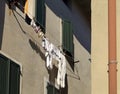 White laundry and underwear hanging out to dry on the drying rack between two home windows