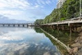 White leading lines of long pier along coastline to historic railway bridge