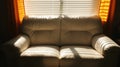 A white leather couch with orange curtains and blinds. Royalty Free Stock Photo