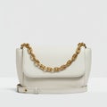 White leather handbag with a structured rectangular design, featuring a prominent gold Royalty Free Stock Photo