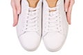 White leather male sneakers shoes on laces in hand