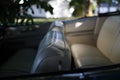 White leather seats in an American convertible under a tree.