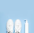 White leather sneakers, plastic bottles of cleaning products for shoes on blue background flat lay top view. Natural leather shoe