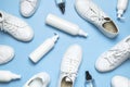 White leather sneakers, plastic bottles of cleaning products for shoes on blue background flat lay top view. Natural leather shoe
