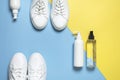 White leather sneakers, plastic bottles of cleaning products for shoes on blue yellow background flat lay top view. Natural