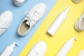 White leather sneakers, plastic bottles of cleaning products for shoes on blue yellow background flat lay top view. Natural