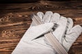 White leather welding glove and welding electrodes on a wooden background. Studio photo in hard light