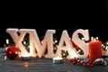 White letters Xmas on Christmas decoration background. Burning candles, holiday wreath on a bokeh light Royalty Free Stock Photo