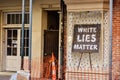 White lies matter sign by the old store front window surrounded by construction.