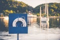 A white lifebuoy ring inside of a blue box on the background of a boats on the body of water Royalty Free Stock Photo