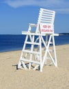 White lifeguard chair on empty sand beach with blue sky