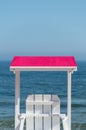 White lifeguard chair visible from the back with a pink visor against the background of a beautiful blue sea and sky on a summer s Royalty Free Stock Photo